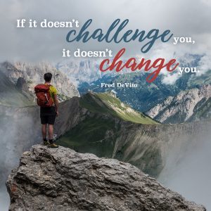 a person standing on a mountain with words about challenge